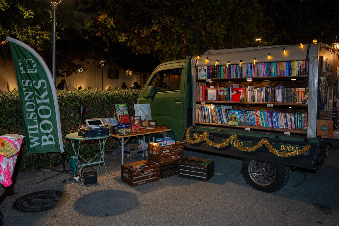 Visitors and shelves of books at the illuminated mobile bookshop.