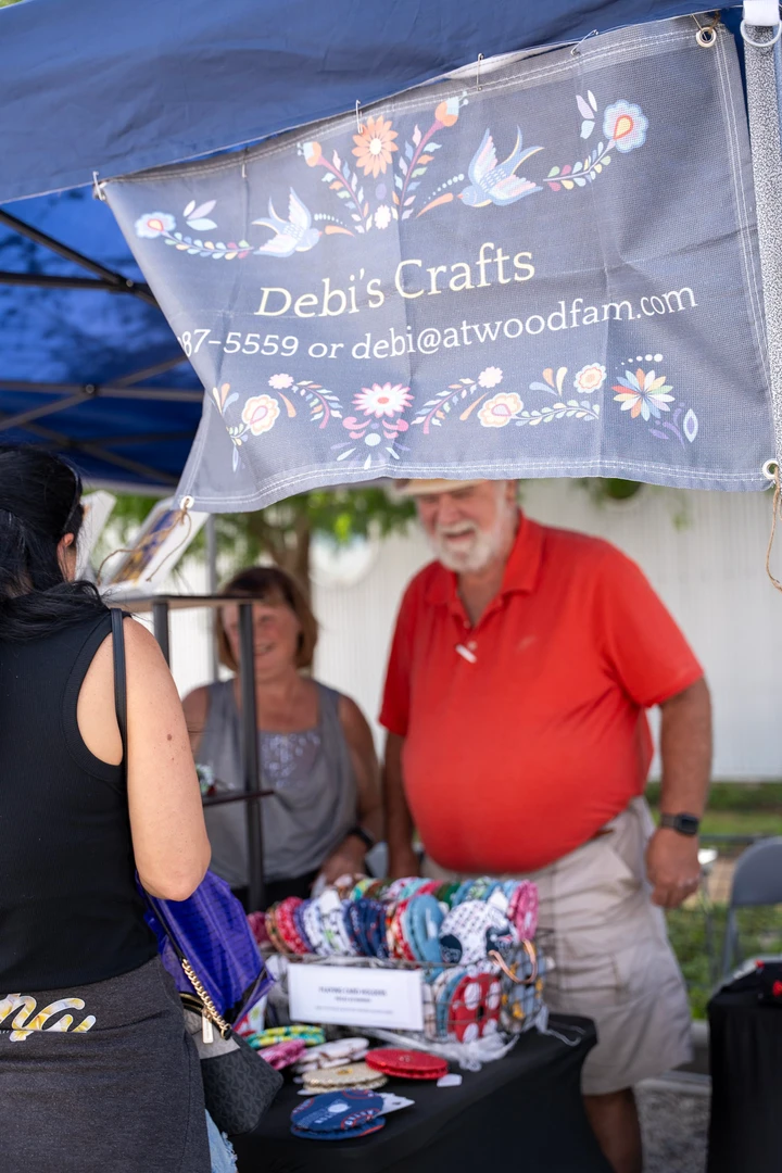 A maker beneath a blue craft-stall canopy.