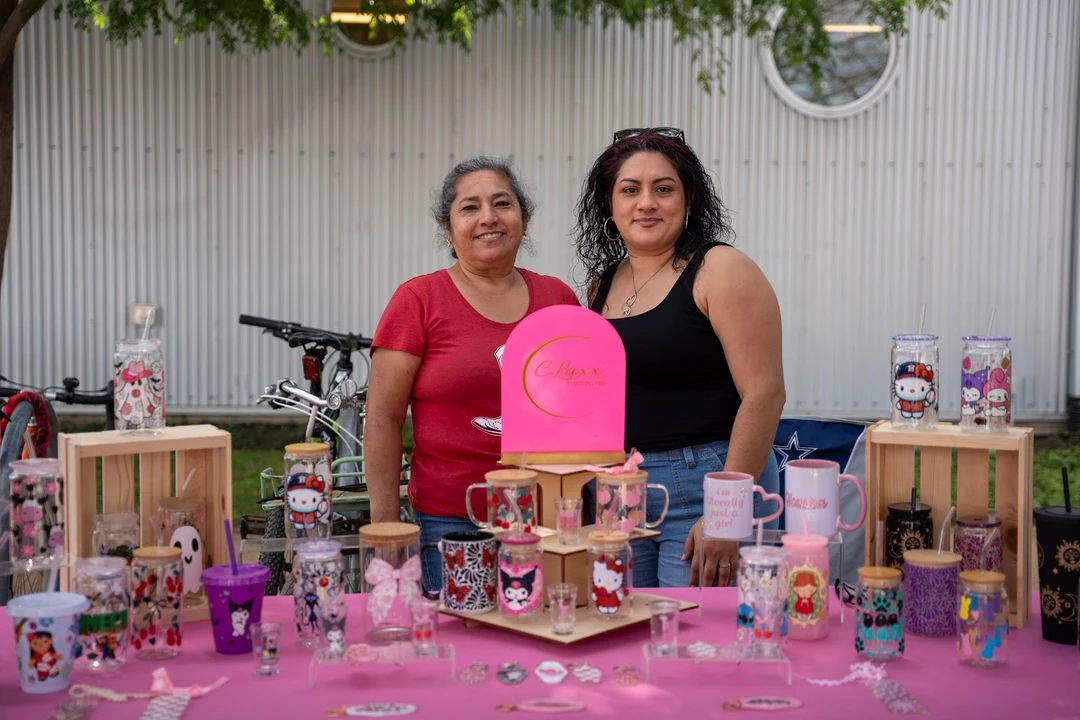 Two makers behind a bright pink jewelry display.