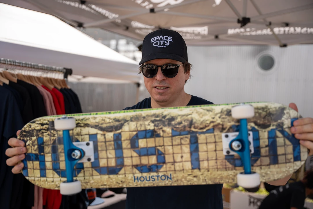 A vendor holding a Houston skateboard deck.