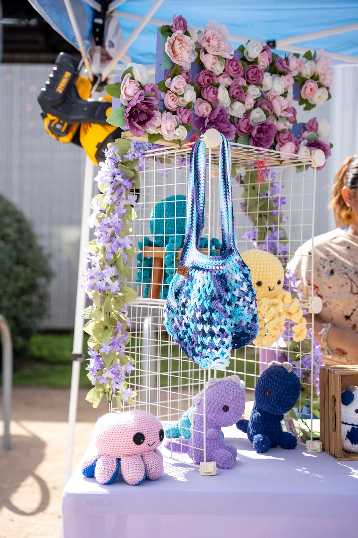 Crocheted flowers and small animals hanging at a market stall.