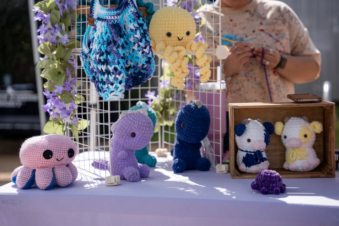 Crocheted animals and flowers on a market table.