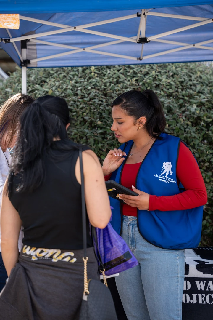 Two people talking beneath a vendor canopy.