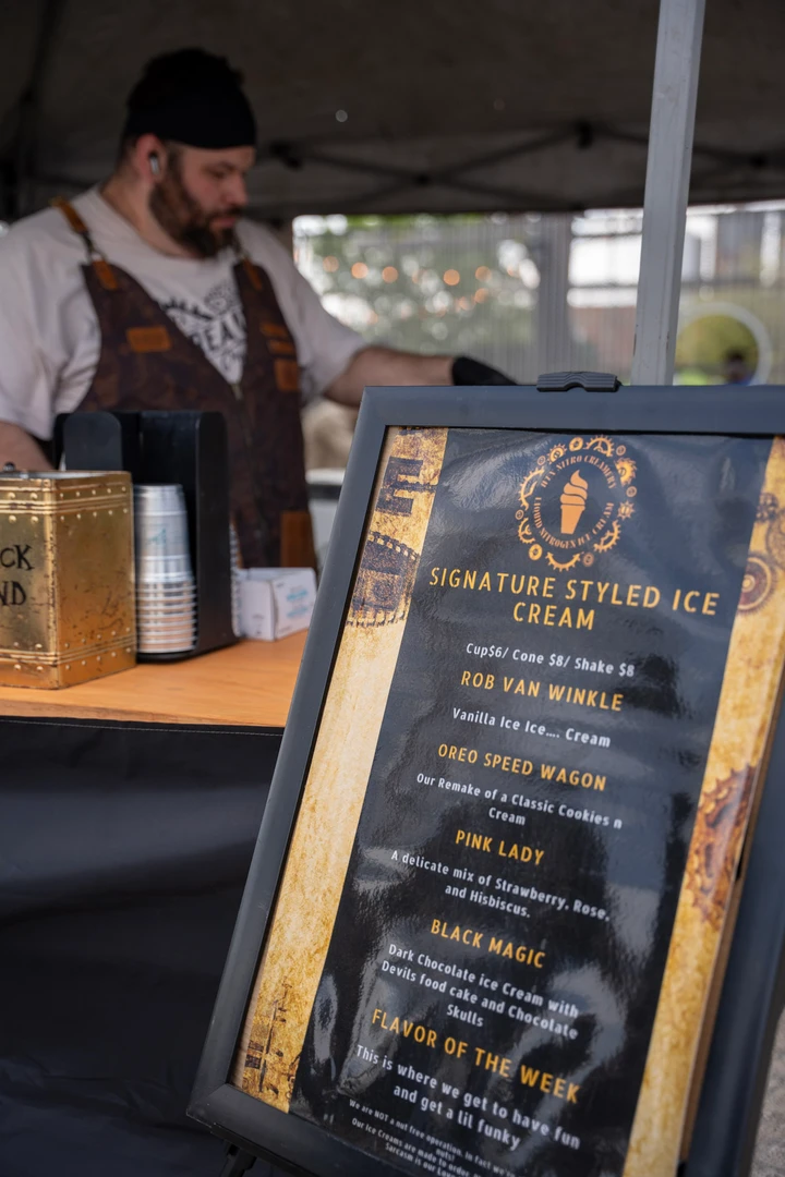 A drinks menu beside a vendor working behind the counter.