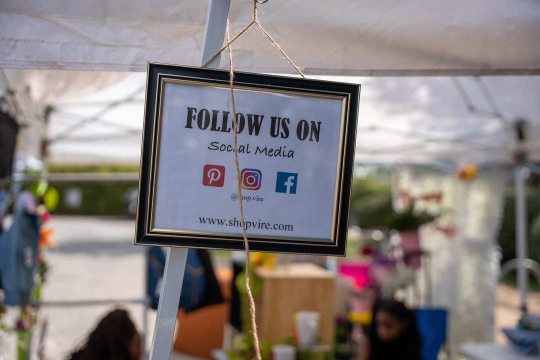 A framed follow-us sign hanging at a market stall.
