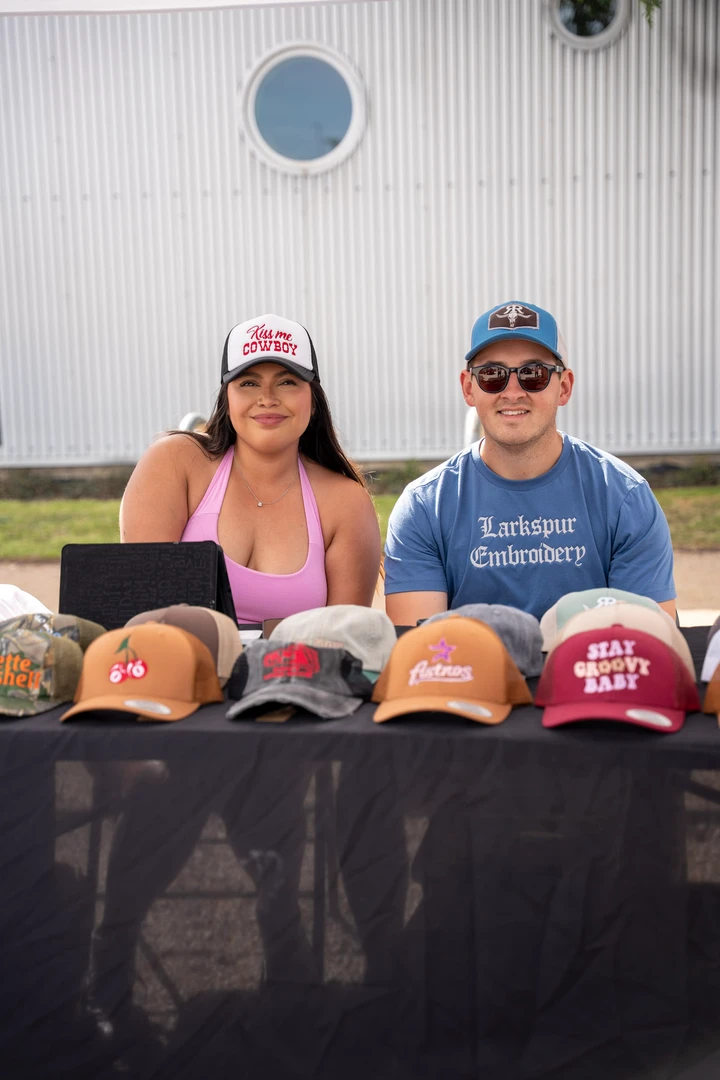 Two vendors behind a display of caps.