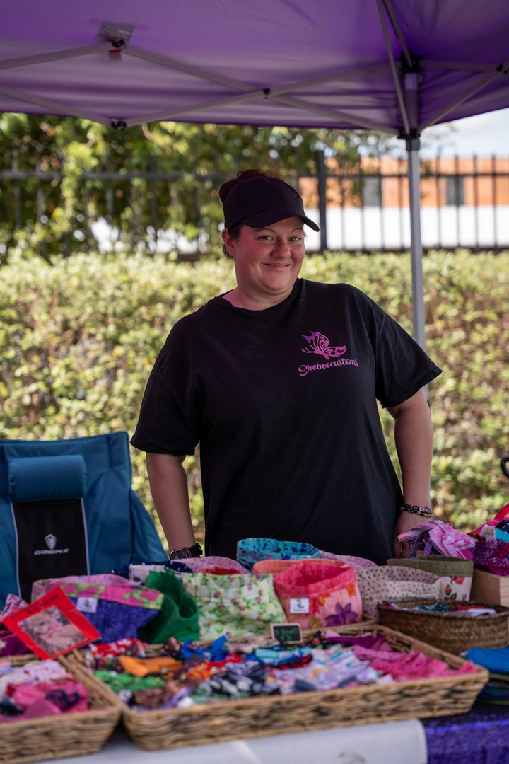 A maker beneath a purple canopy with colorful crafts.