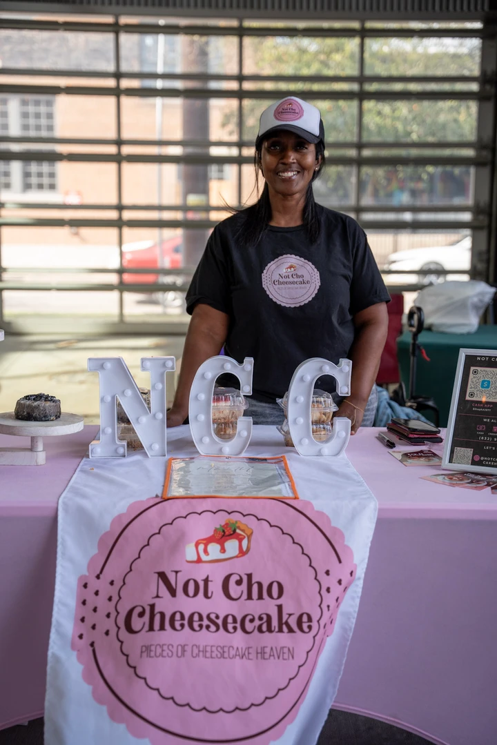A vendor behind a Not Cha Cheesecake table.