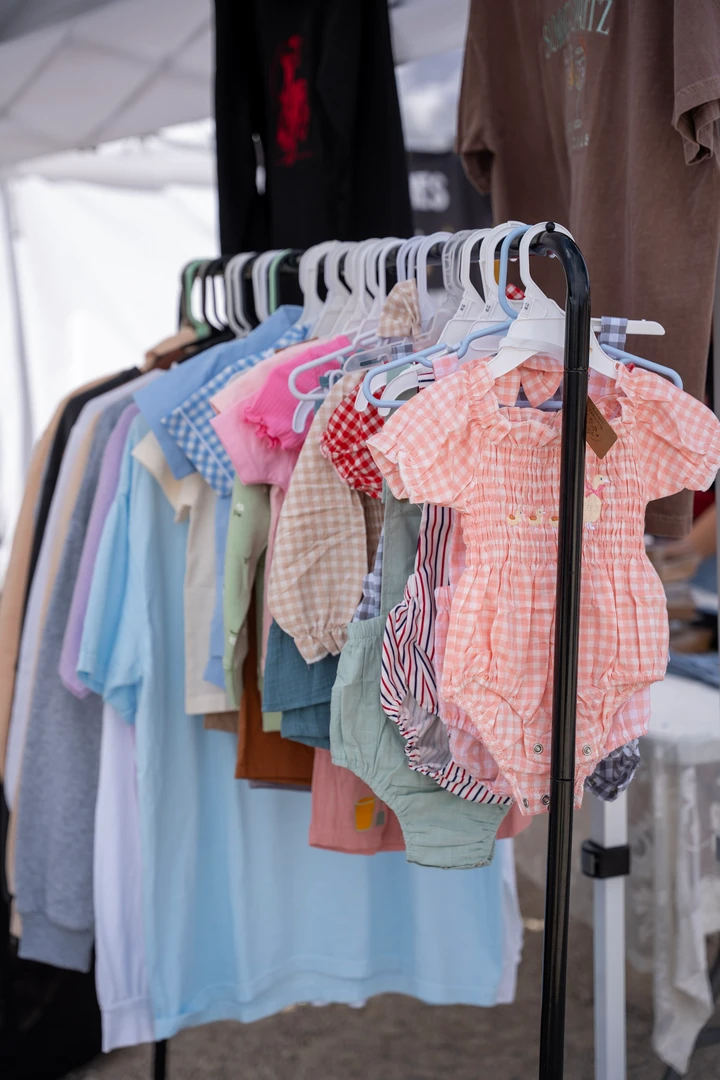 Pastel shirts hanging beneath a market canopy.