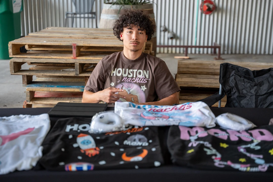 A vendor seated behind folded printed clothing.