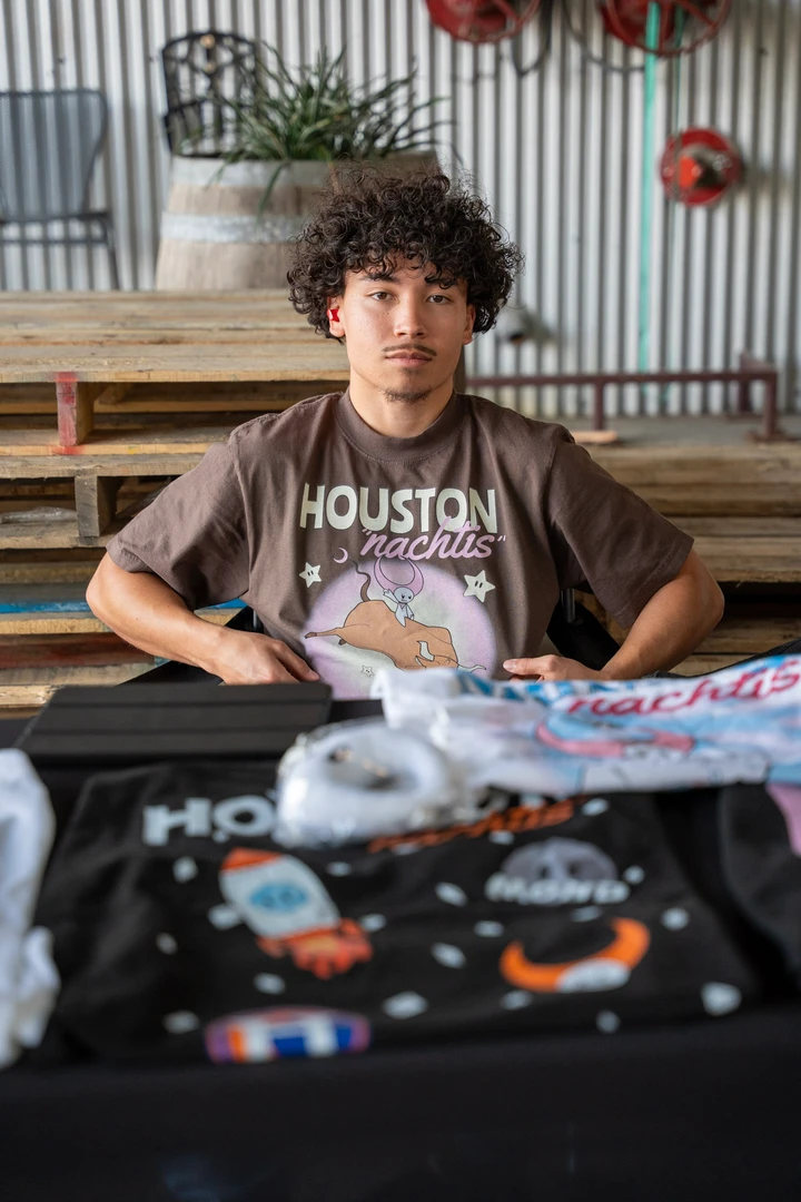 A vendor seated behind folded printed clothing.