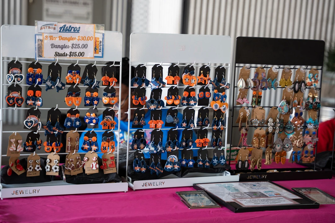 Rows of colorful earrings displayed on a pink table.