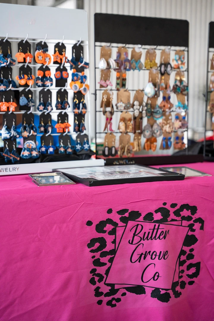 Rows of colorful earrings displayed on a pink table.