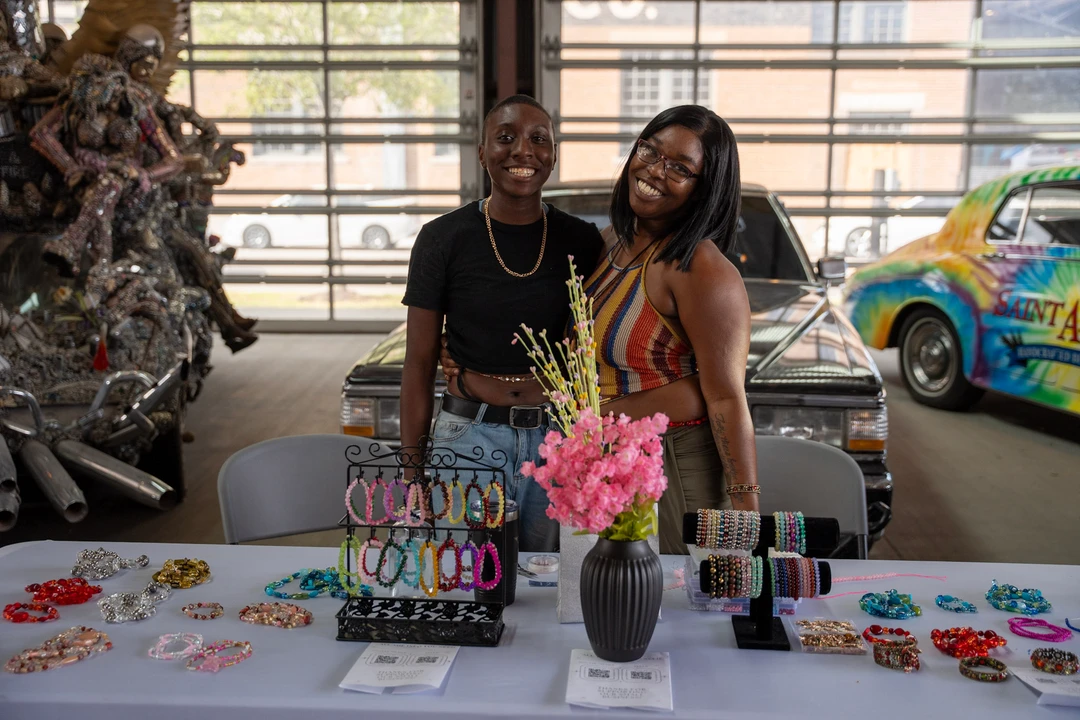Two vendors behind a colorful accessories table.