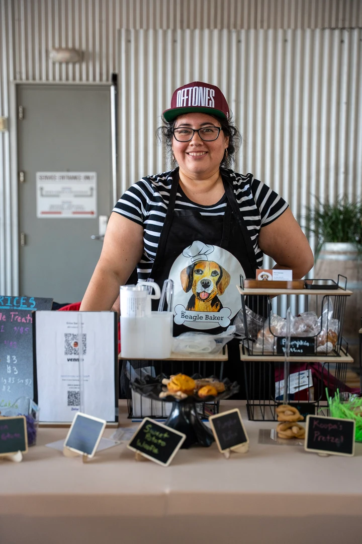 A vendor behind small labeled jars and products.