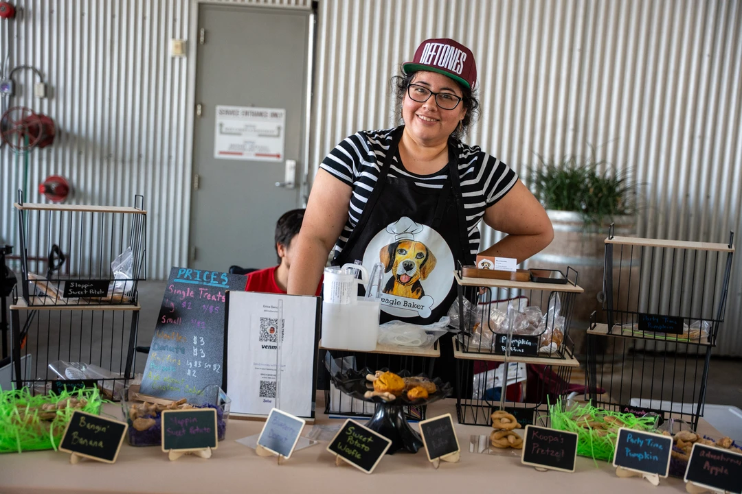 A vendor behind small labeled jars and products.