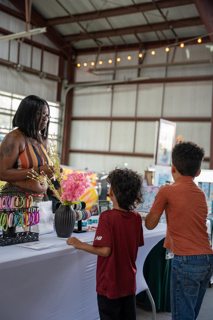 Visitors browsing indoor market tables.