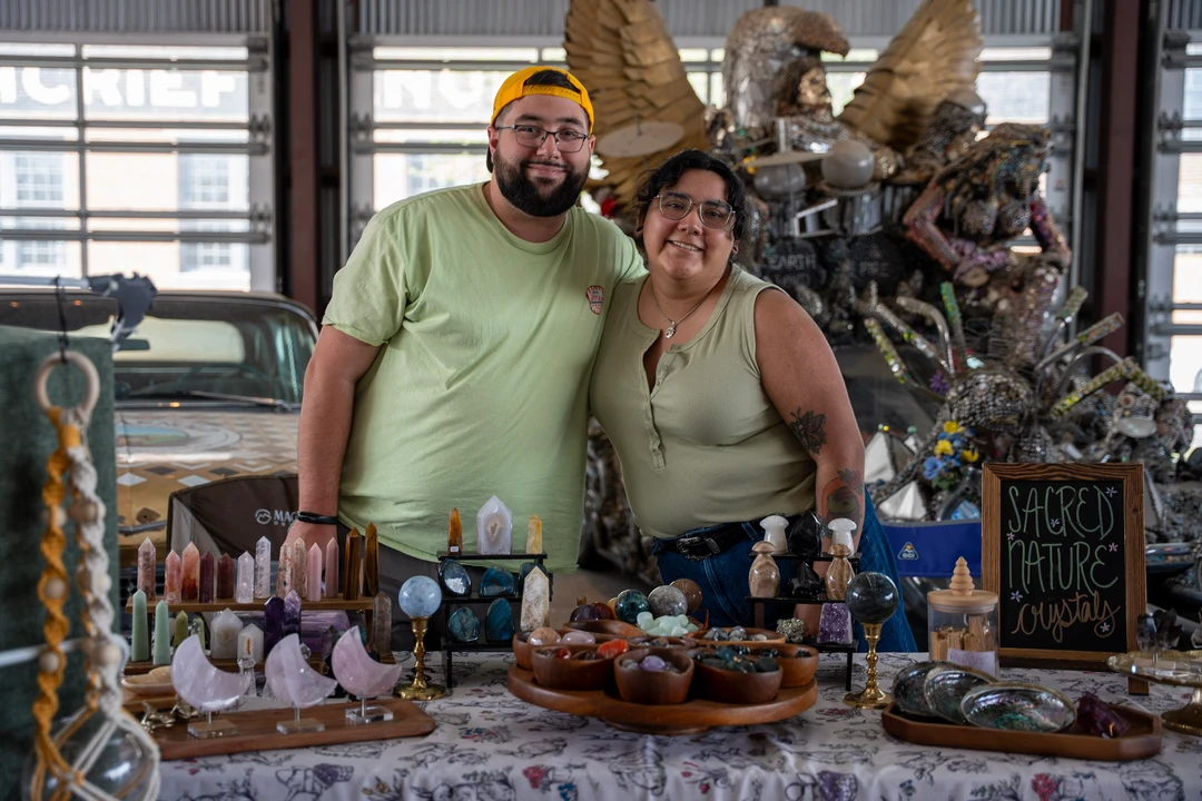 Two makers behind a table of pottery and crafts.