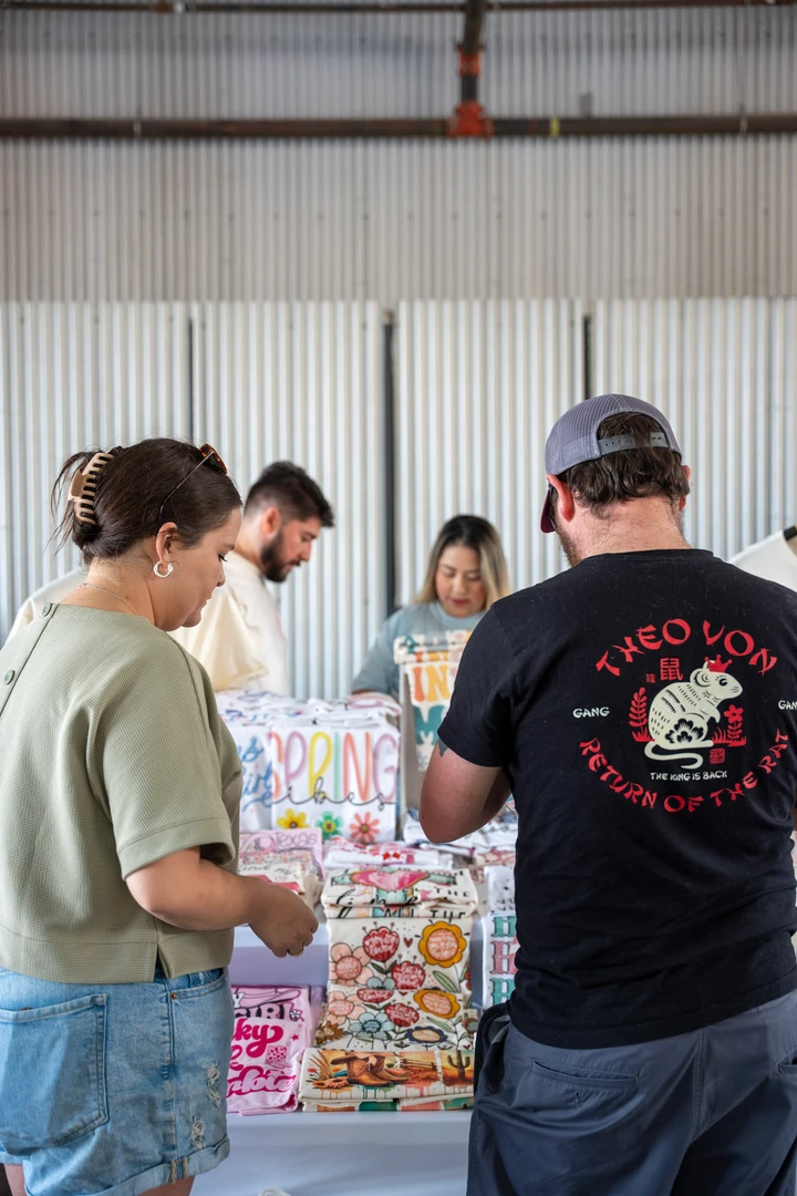 Visitors talking with a maker across a market table.