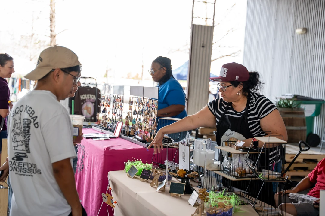 Visitors talking with a maker across a market table.