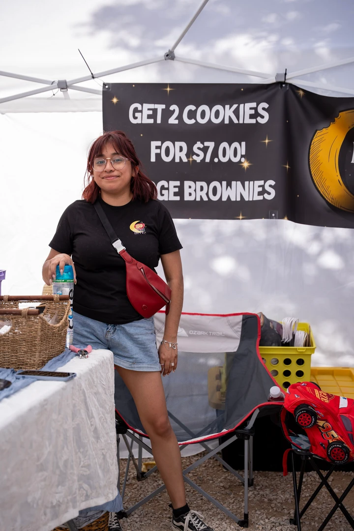 A vendor beside a cookie and brownie stall.