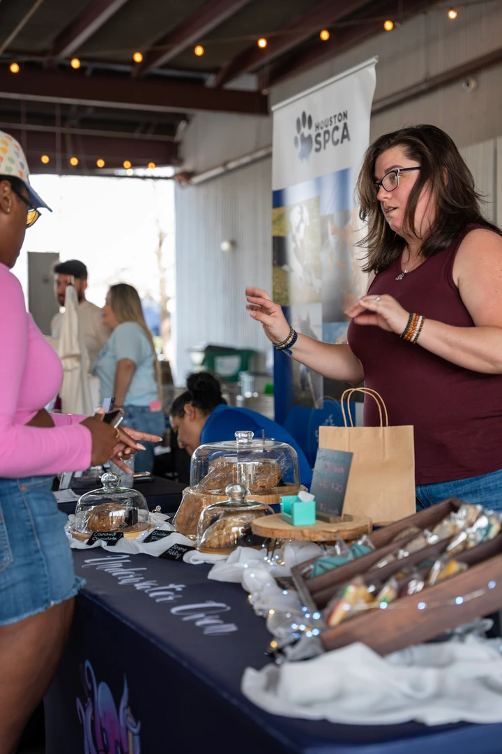 A maker arranging items on an indoor market table.