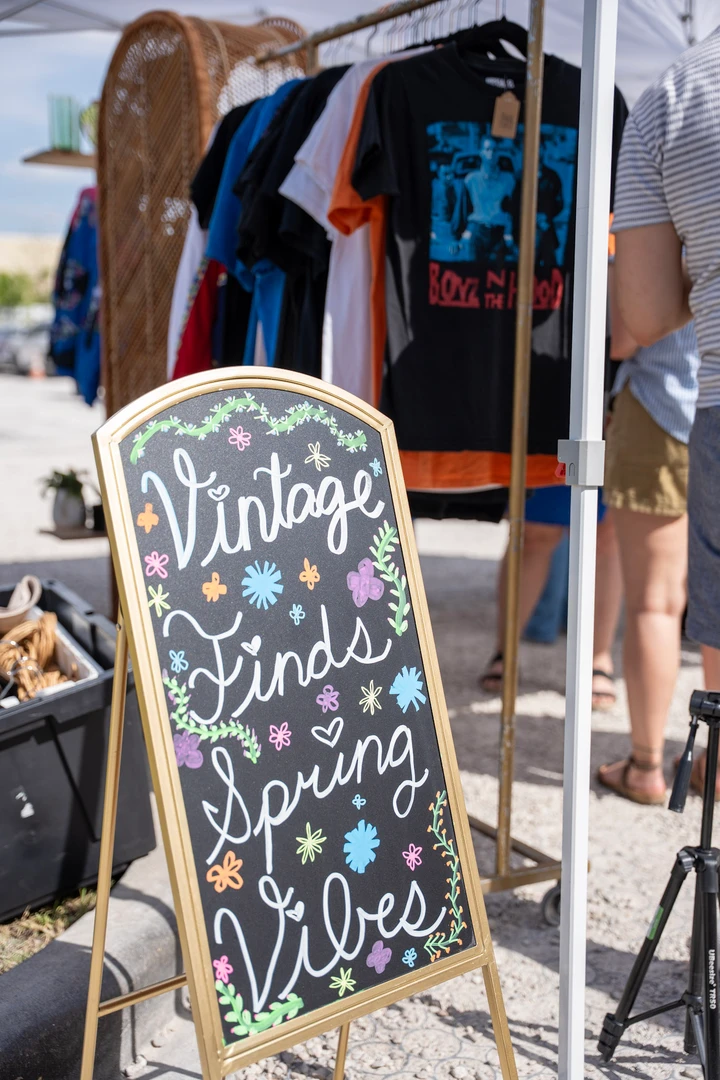 A vintage clothing sign beside a rack of shirts.