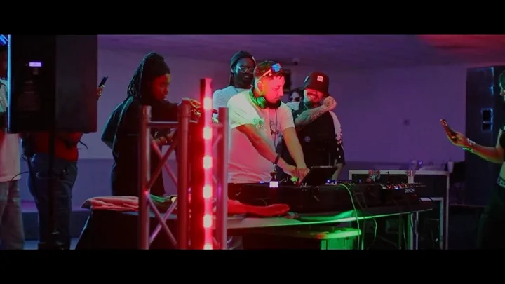 Performers and a DJ under colorful event lights.